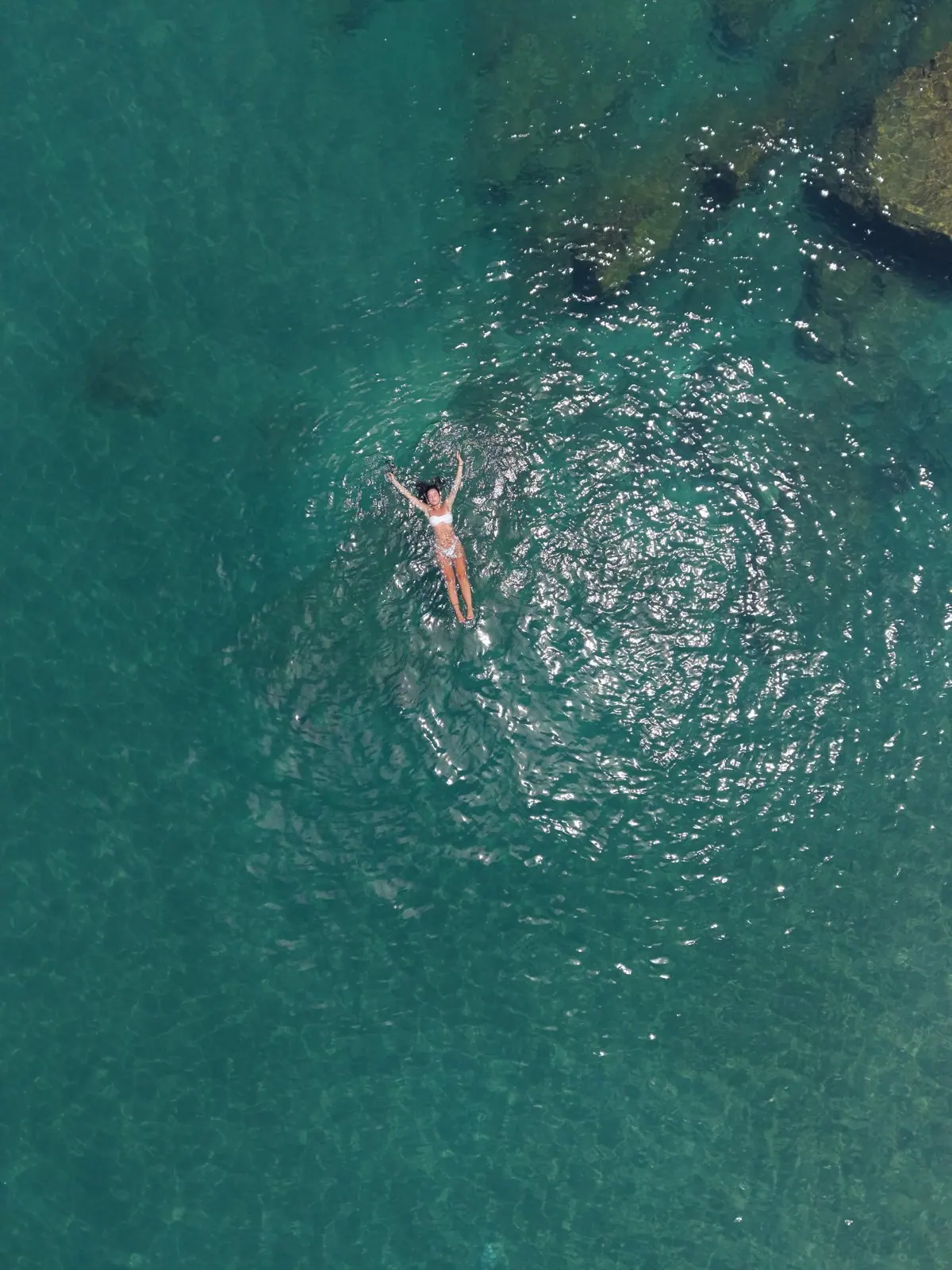 Banhista boiando no mar verde e transparente perto de uma ilha