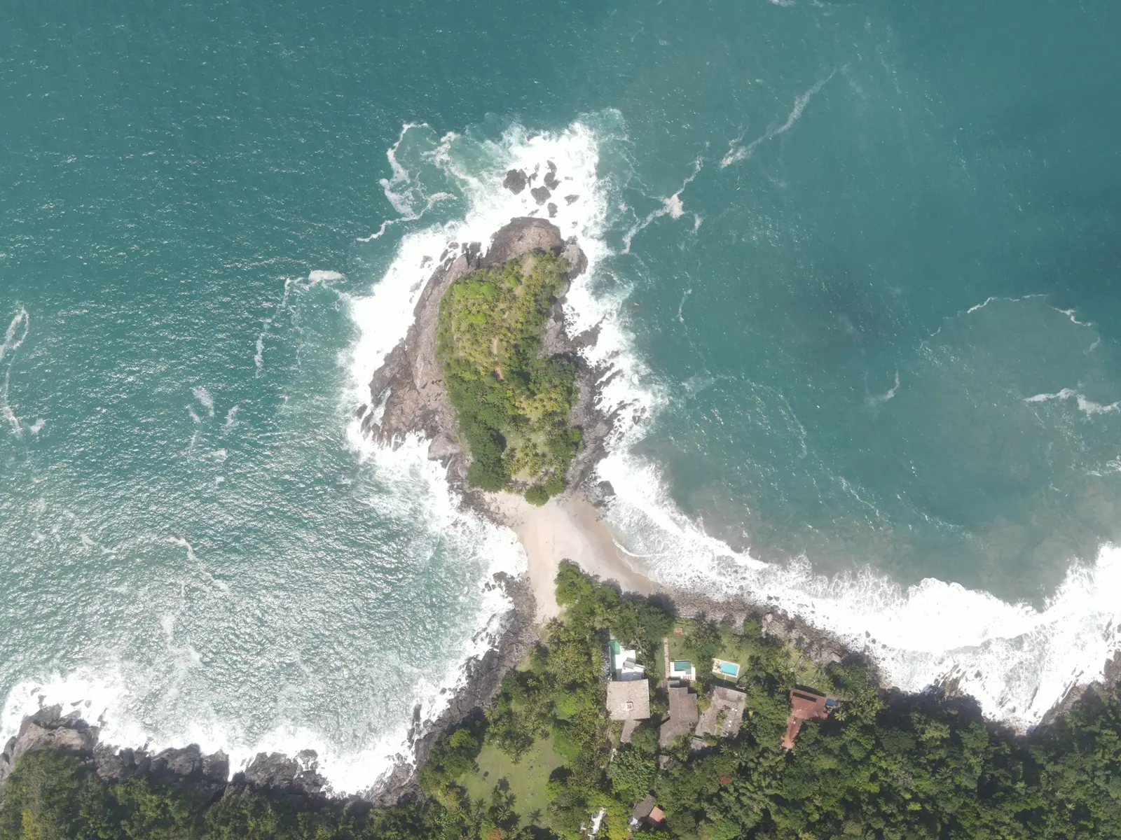 Península de Calhetas vista de cima, com as duas praias de cada lado da faixa de areia e as ondas no costão