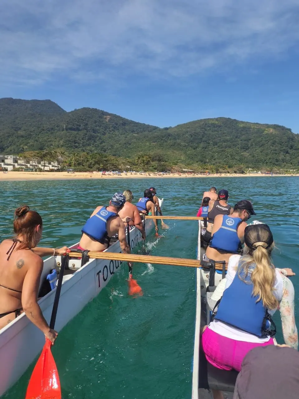 Canoa havaiana com a praia e a serra ao fundo