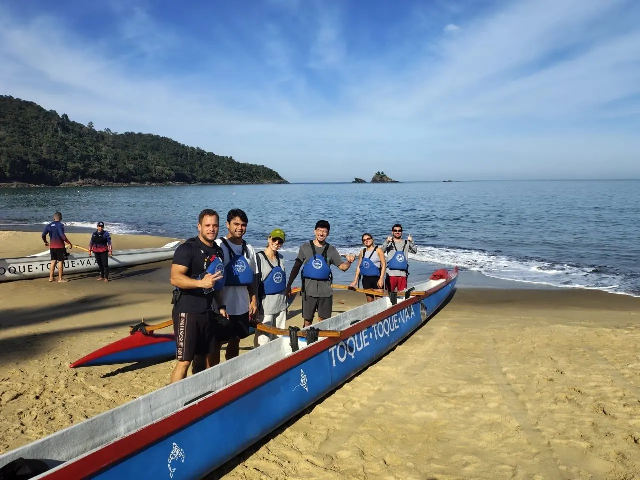 Grupo da Toque Toque Va'a ao lado da canoa havaiana na areia de Toque-Toque Pequeno