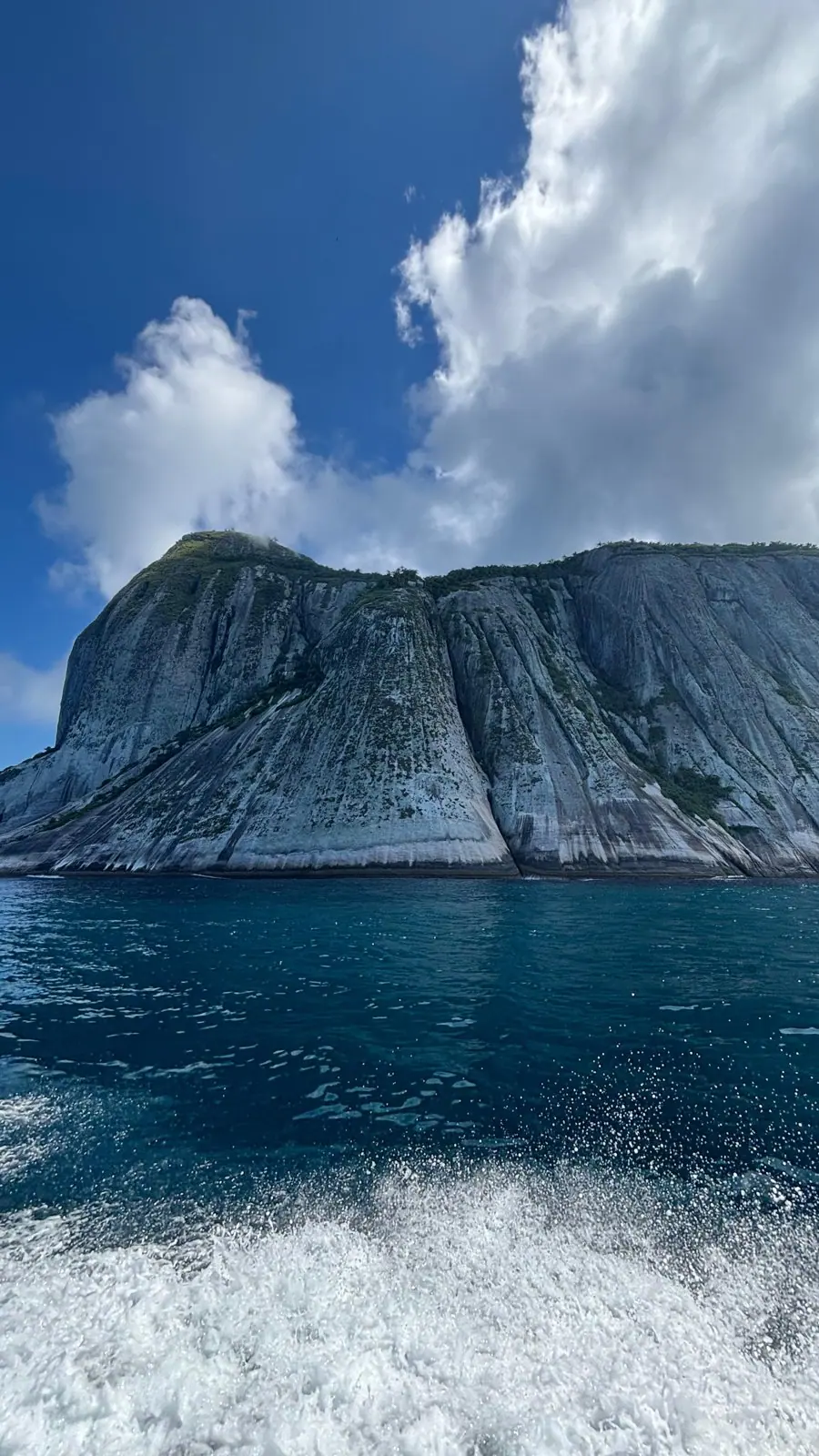 Costão de granito de ilha com o rastro de espuma do barco