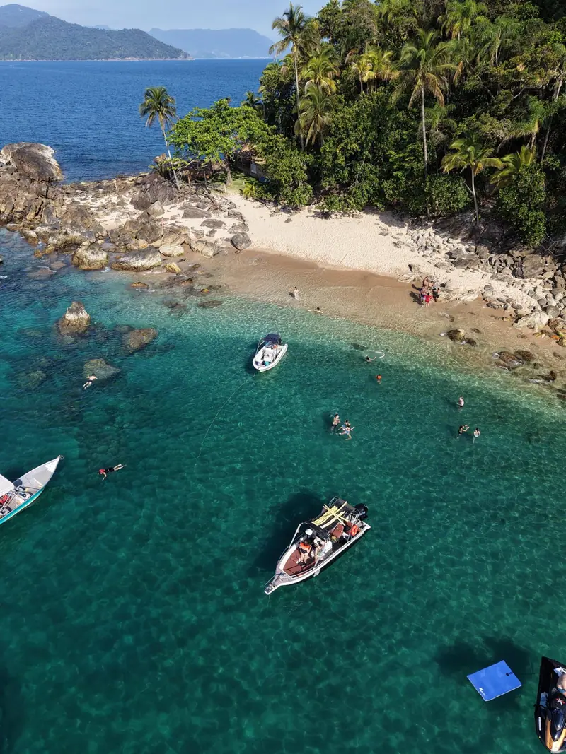 Lanchas ancoradas em enseada de areia clara em uma ilha do litoral norte, vista do alto