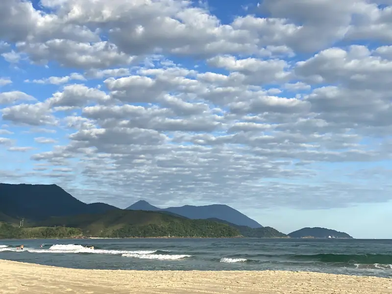 Mar calmo e montanhas vistos da areia da Praia de Santiago