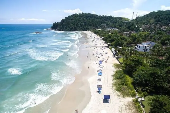 Praia de Camburizinho vista do alto, com a faixa de areia, o mar e o morro no canto
