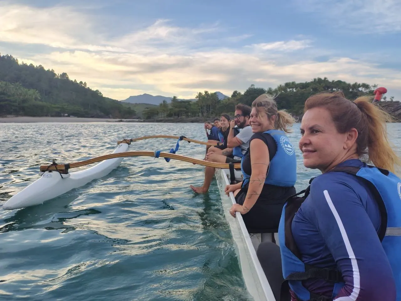 Remadoras descansando na canoa havaiana, com a serra ao fundo