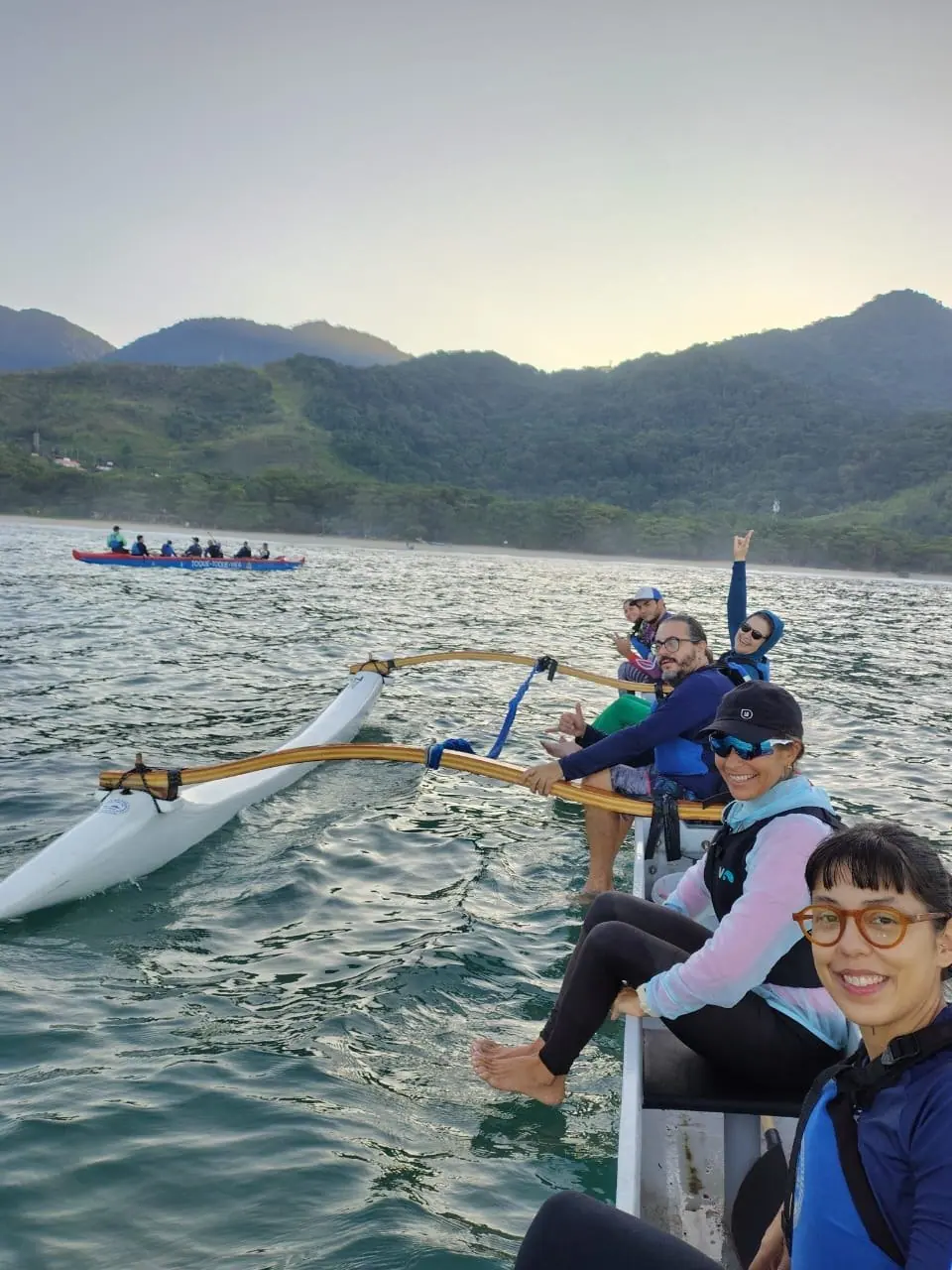 Remadores acenando na canoa havaiana em dia de mar calmo