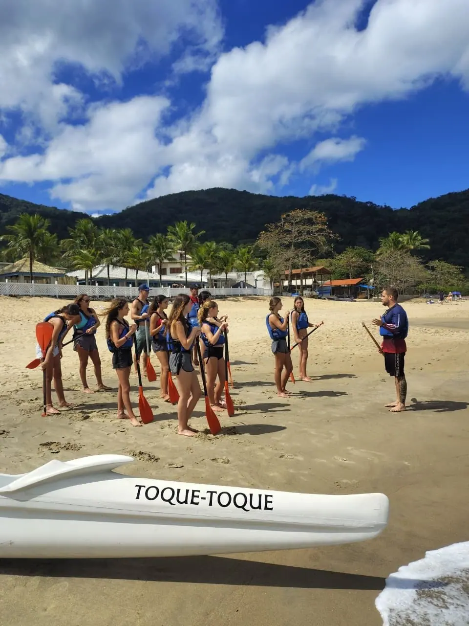Remadores com remos na areia de Toque-Toque Pequeno, prontos para entrar no mar