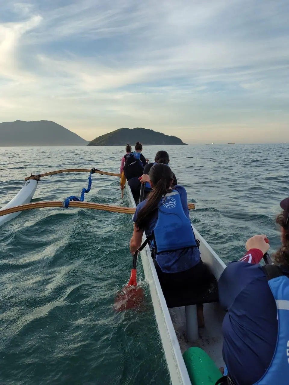 Remadores em fila na canoa havaiana, remando no mesmo ritmo