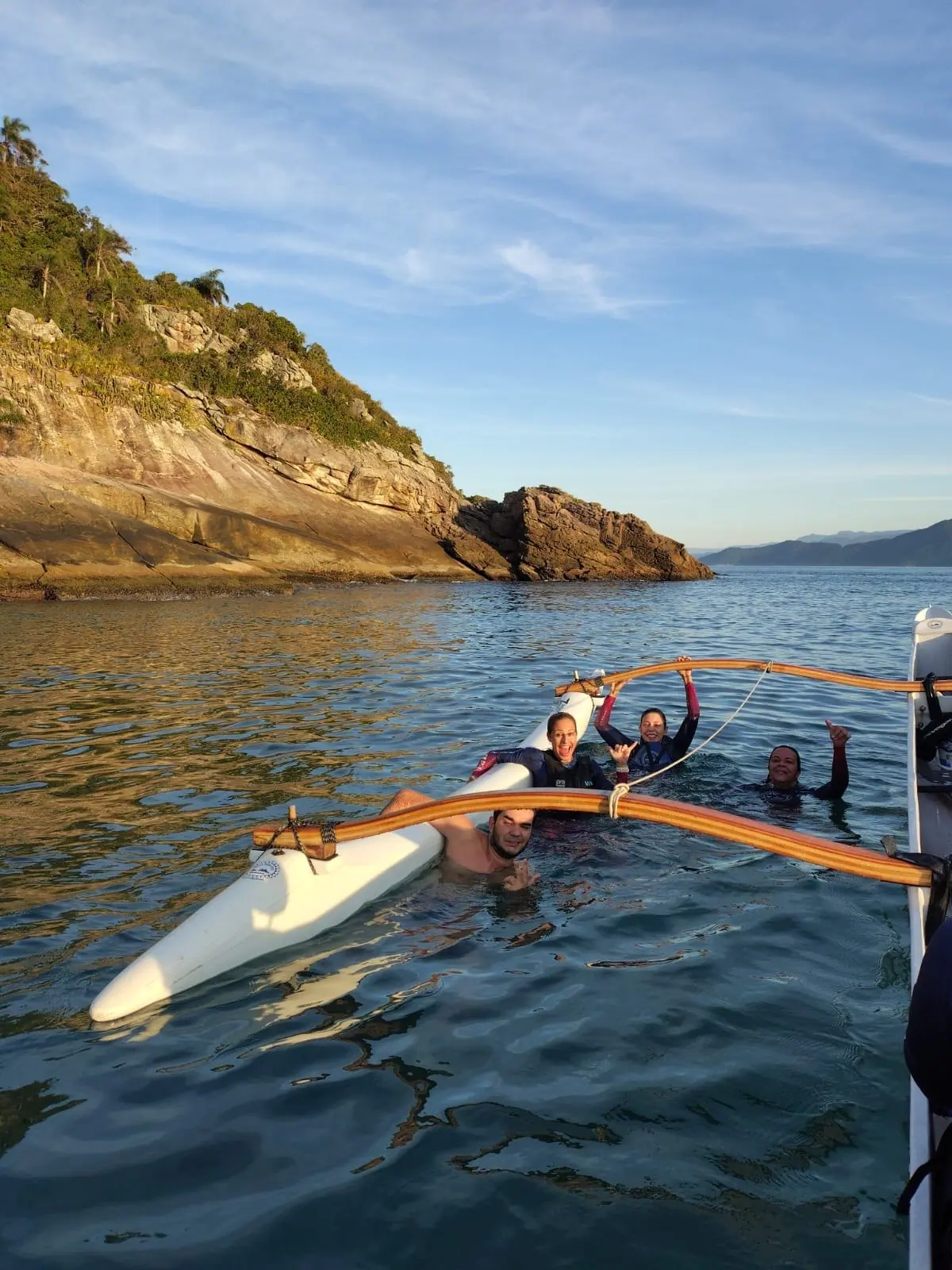 Remadores de colete na água ao lado da canoa havaiana