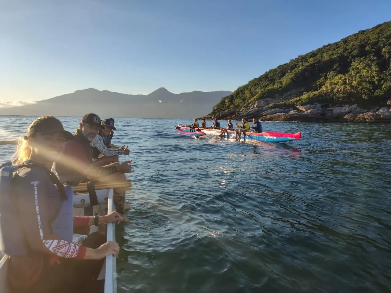 Remadores parados na canoa havaiana olhando as ilhas da Costa Sul