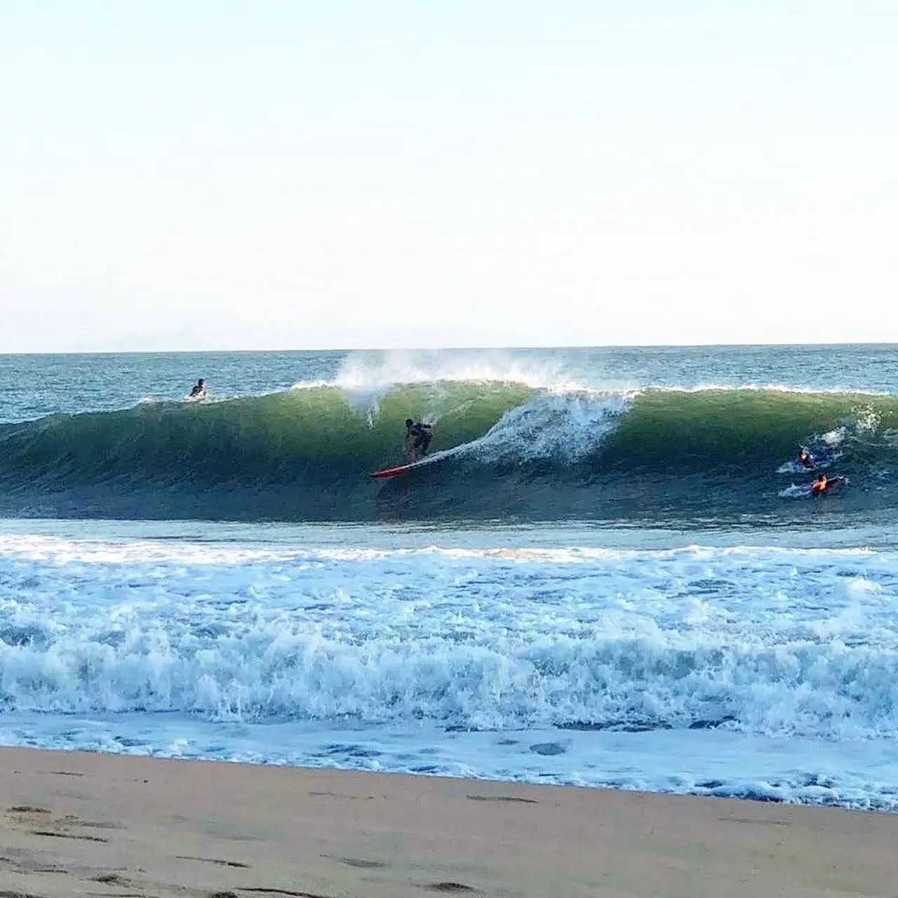 Surfista entubando em Paúba, com a espuma da onda saindo do tubo