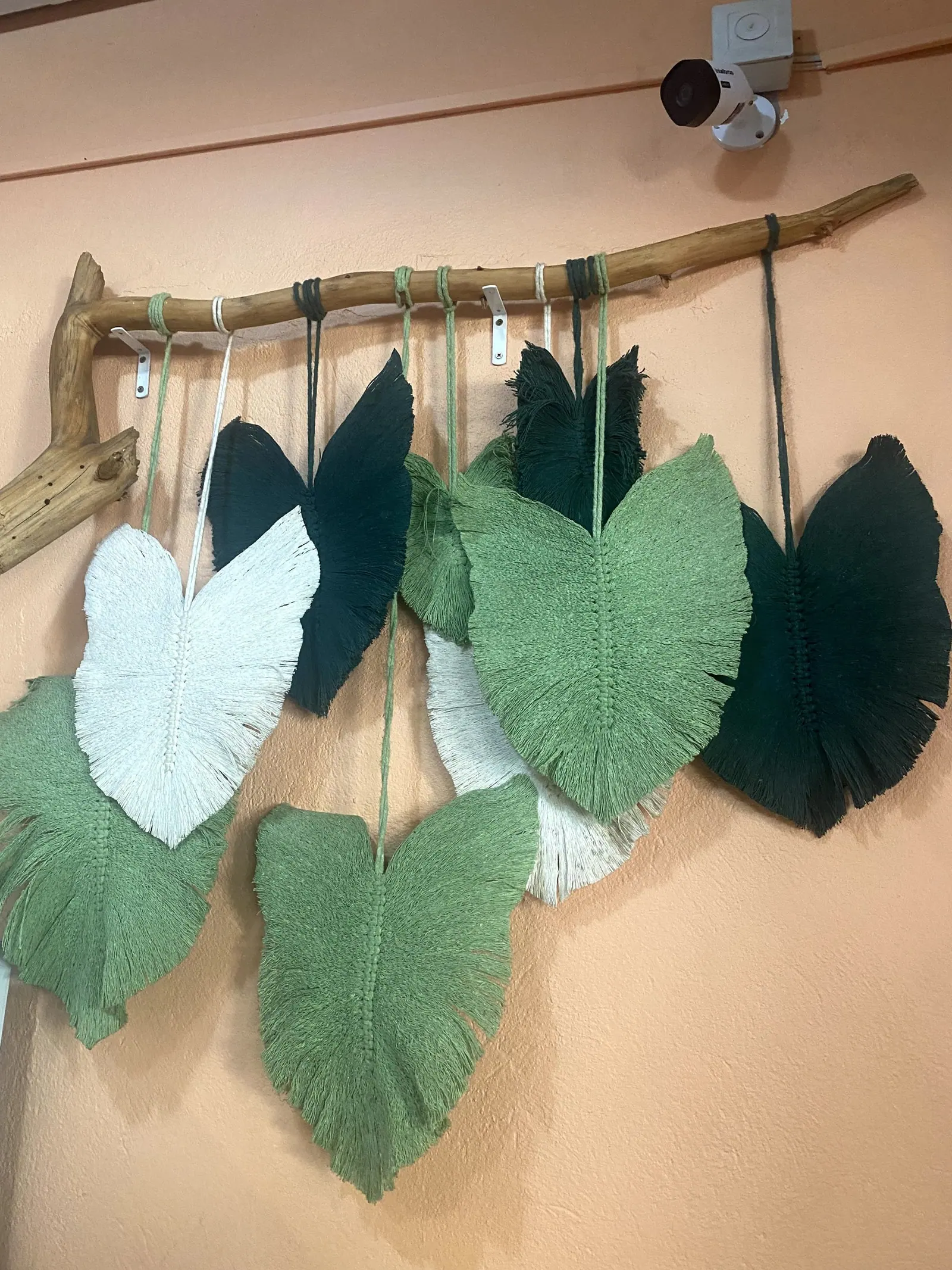 Decoração de folhas de macramê em tons de verde na parede do restaurante Taioba