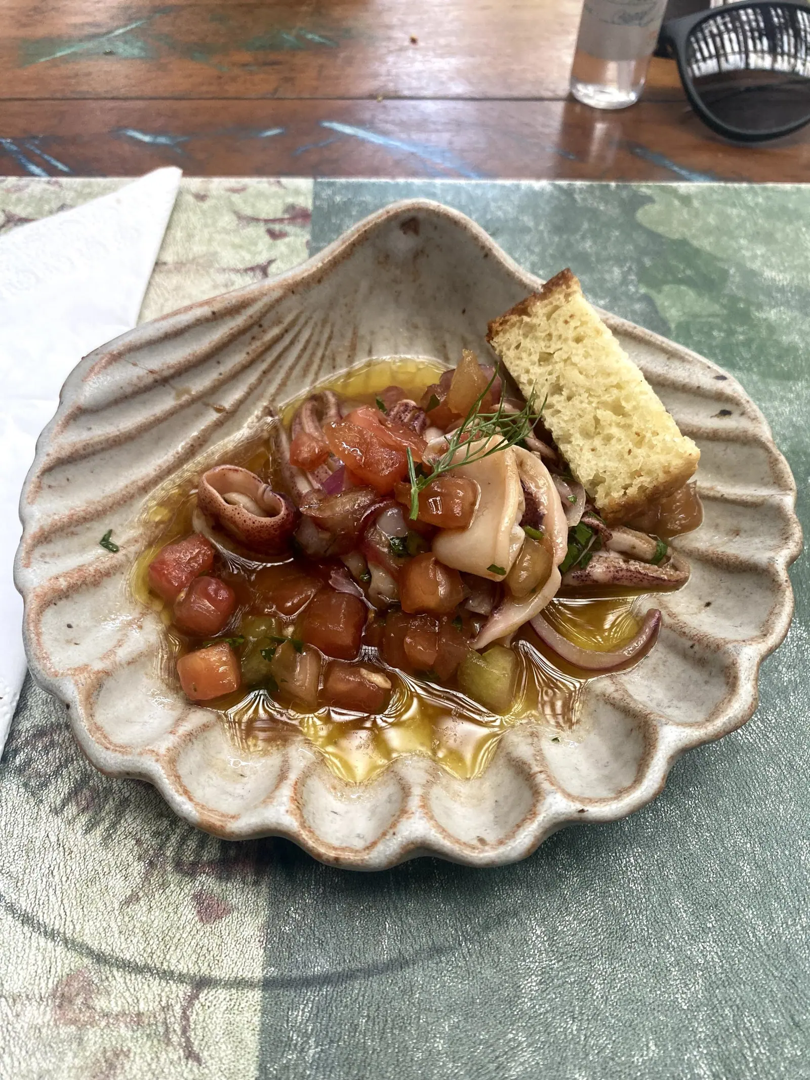 Lulas à vinagrete com tomate e cebola, servidas em prato de concha com pão, no Taioba