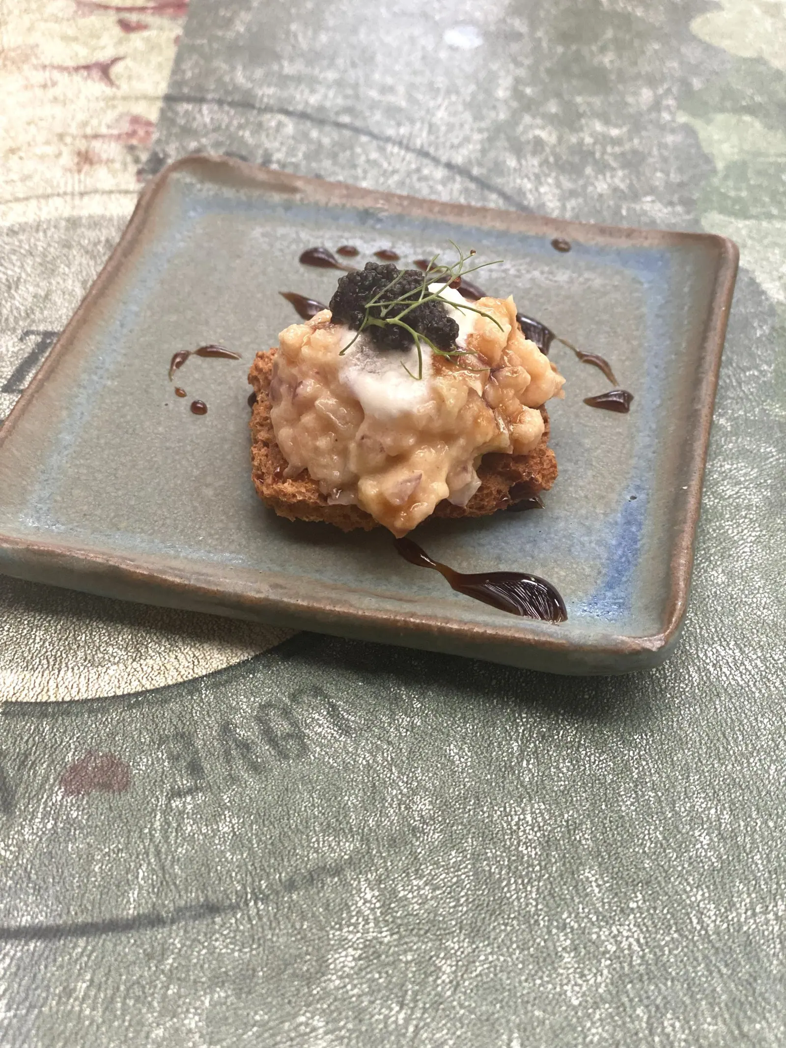 Torrada com tartar e caviar em prato de cerâmica no Taioba