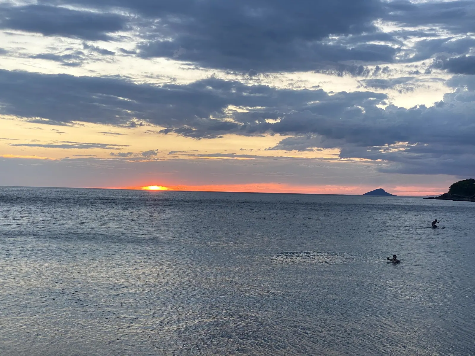 Banhistas no mar calmo de Toque-Toque Grande durante o pôr do sol