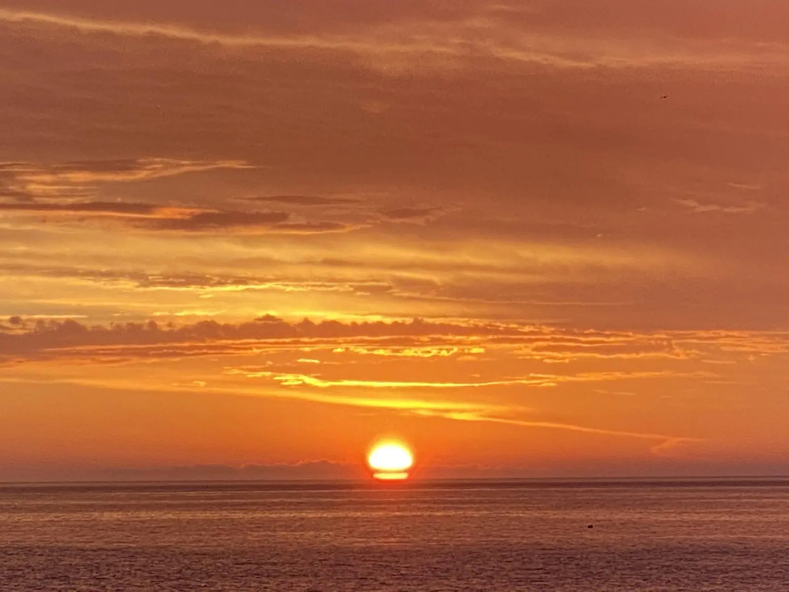 Céu laranja e sol pouco acima do mar em Toque-Toque Grande