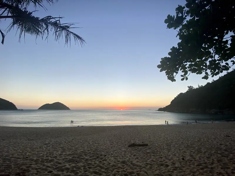 Chegada à praia de Toque-Toque Grande entre as árvores, com a ilha ao fundo