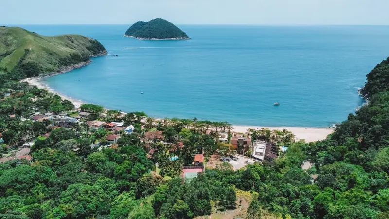 Casas do bairro de Toque-Toque Grande entre a mata e a praia, com a ilha e o morro de capim ao fundo