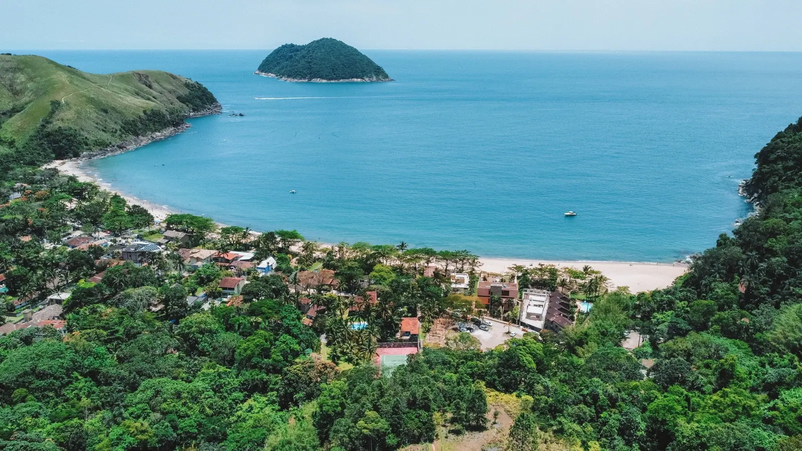 Casas do bairro de Toque-Toque Grande entre a mata e a praia, com a ilha e o morro de capim ao fundo