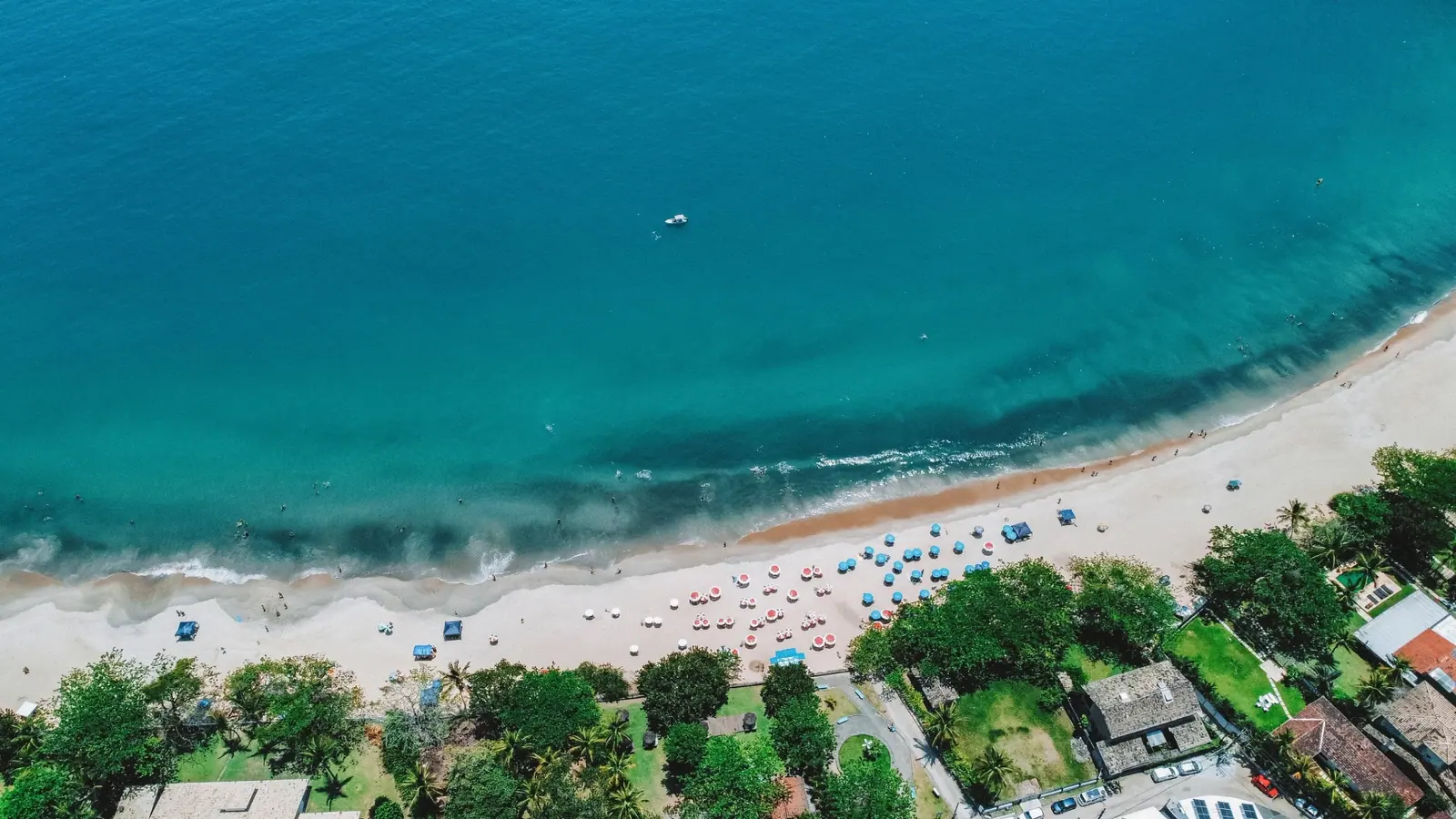 Guarda-sóis na areia e mar azul-turquesa de Toque-Toque Grande vistos de cima