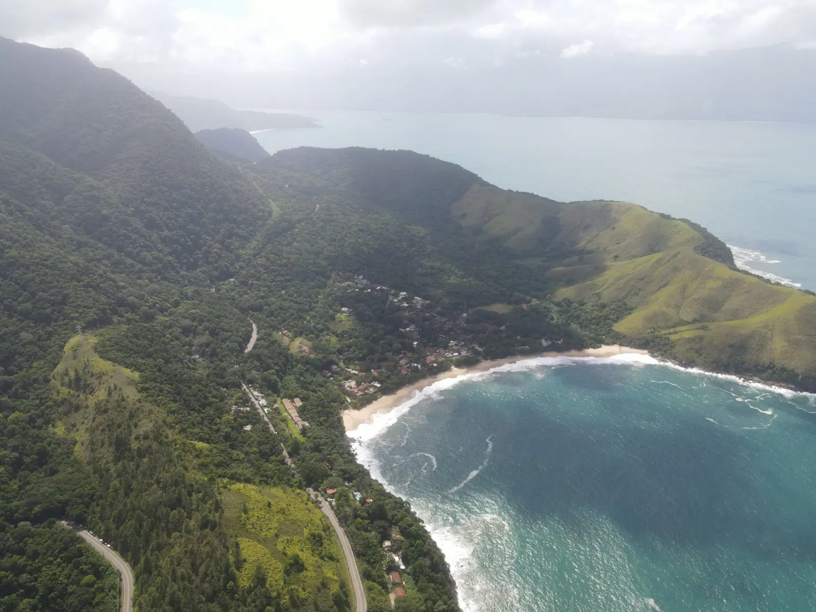 Vista aérea da Rodovia Rio-Santos descendo a serra até a enseada de Toque-Toque Grande, com Ilhabela ao fundo