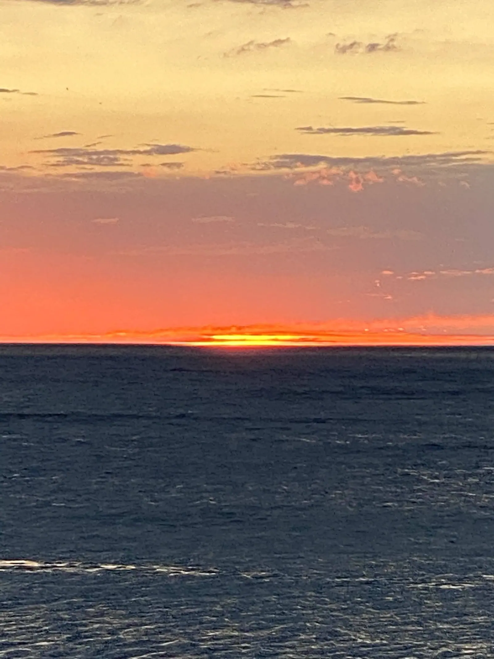 Faixa de sol no horizonte de Toque-Toque Grande sob um céu laranja