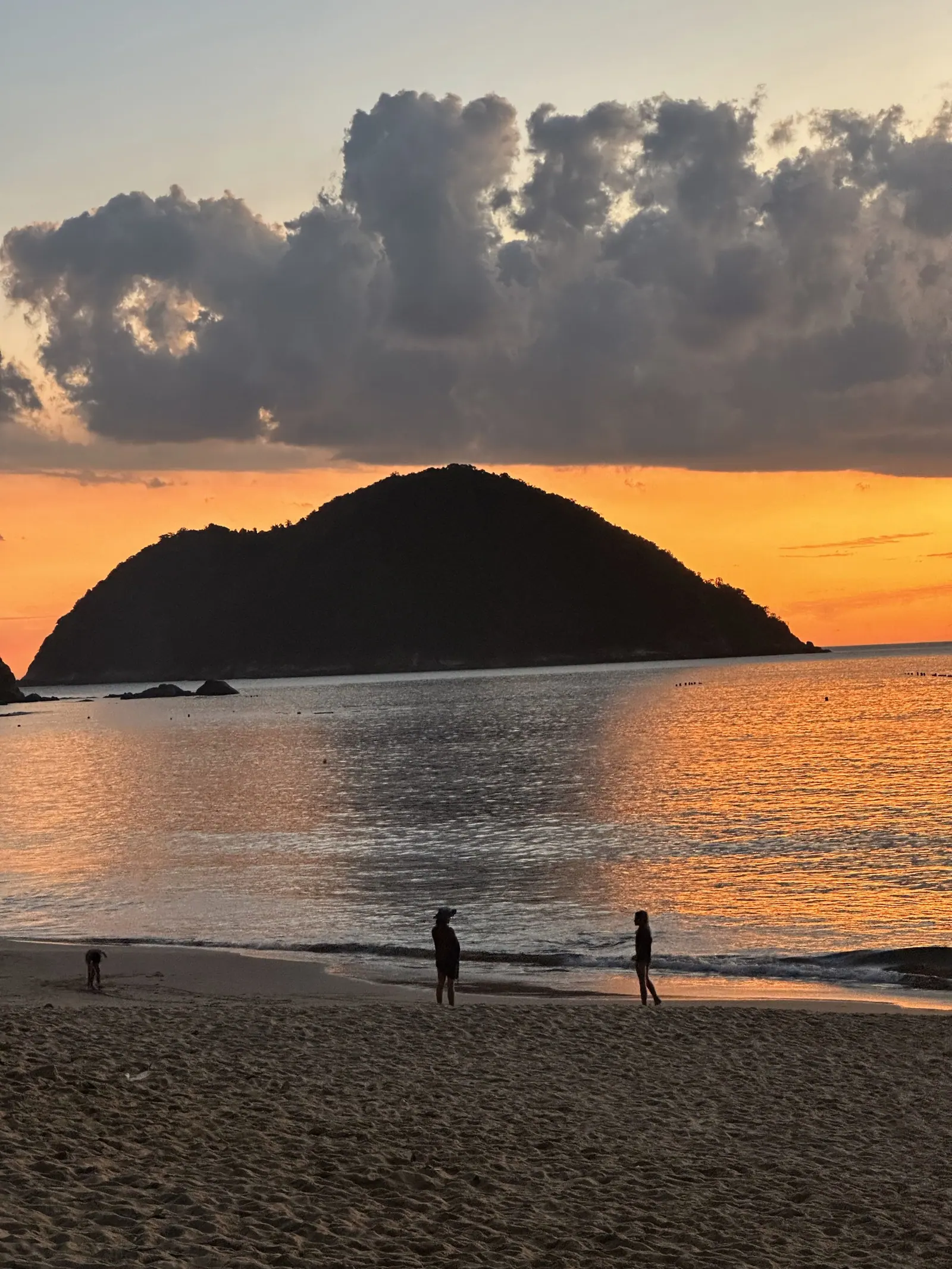 A ilha de Toque-Toque Grande de perto ao entardecer, com pessoas caminhando na areia