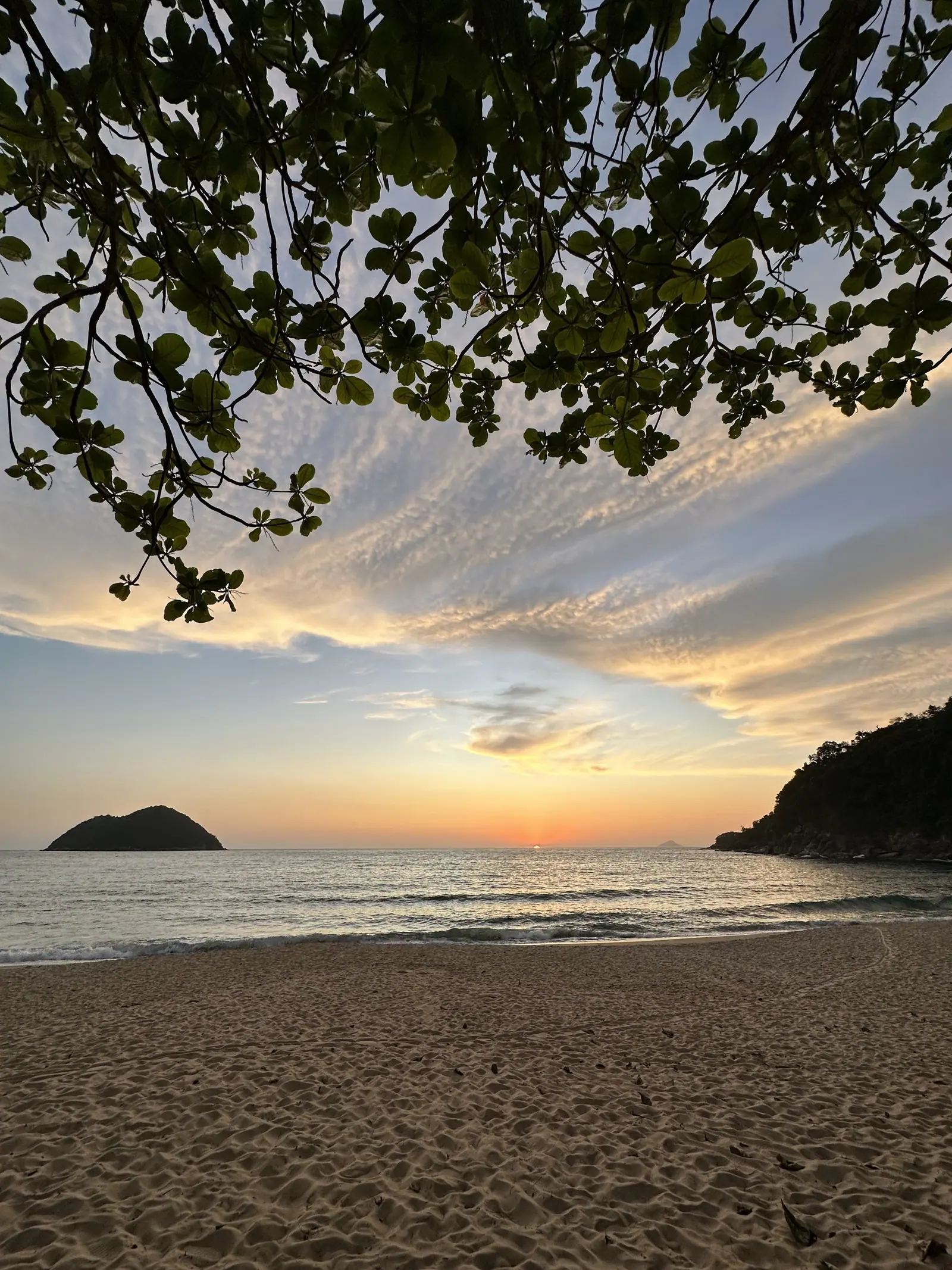 A ilha de Toque-Toque Grande vista da sombra de uma árvore na areia