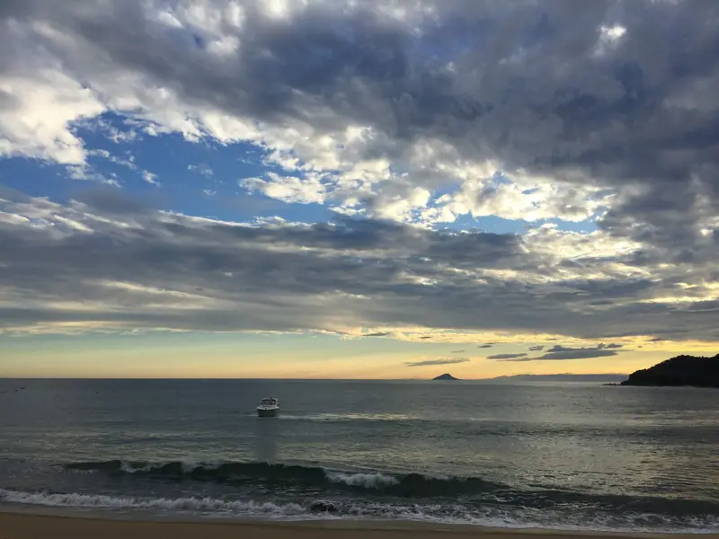 Lancha passando pela enseada de Toque-Toque Grande num fim de tarde nublado
