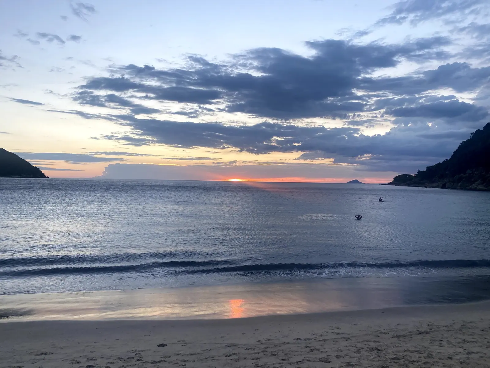 Mar calmo de Toque-Toque Grande no fim da tarde, com banhistas ao longe