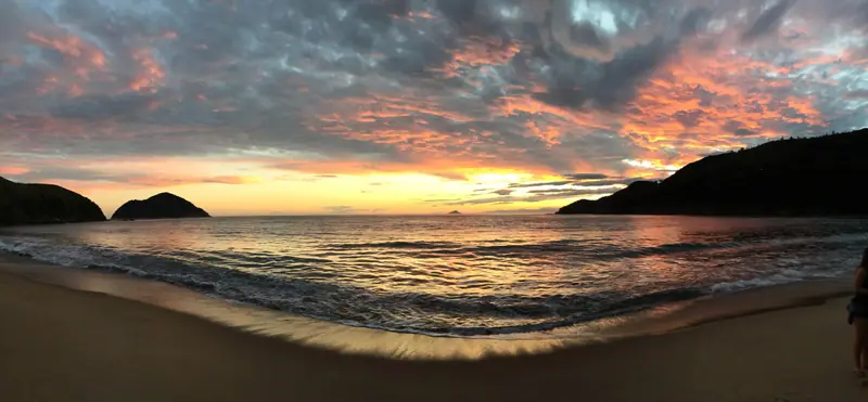 Pôr do sol panorâmico em Toque-Toque Grande, com nuvens coloridas sobre a enseada e as ilhas