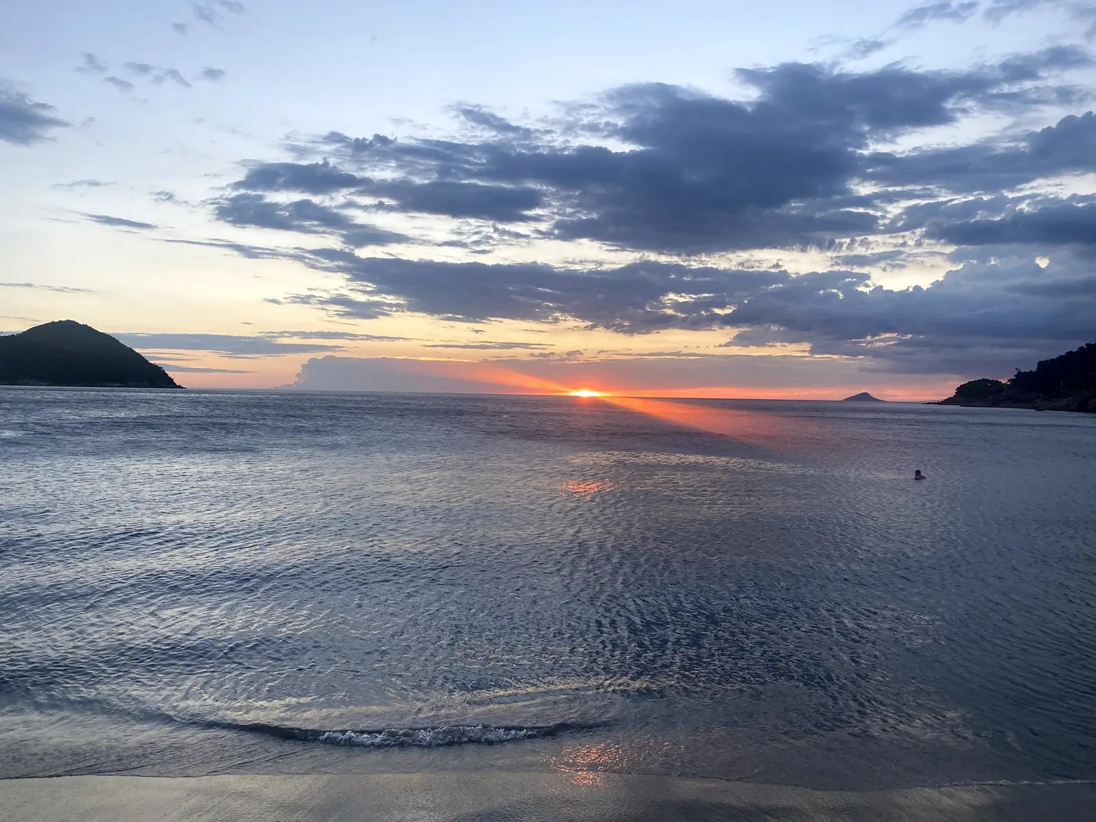 Reflexo do sol na enseada de Toque-Toque Grande, com ilhas e costão