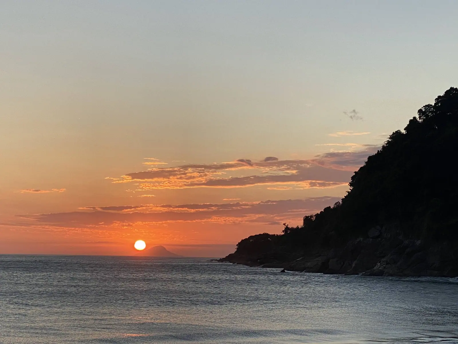 Sol se pondo entre o costão e uma ilha no horizonte de Toque-Toque Grande