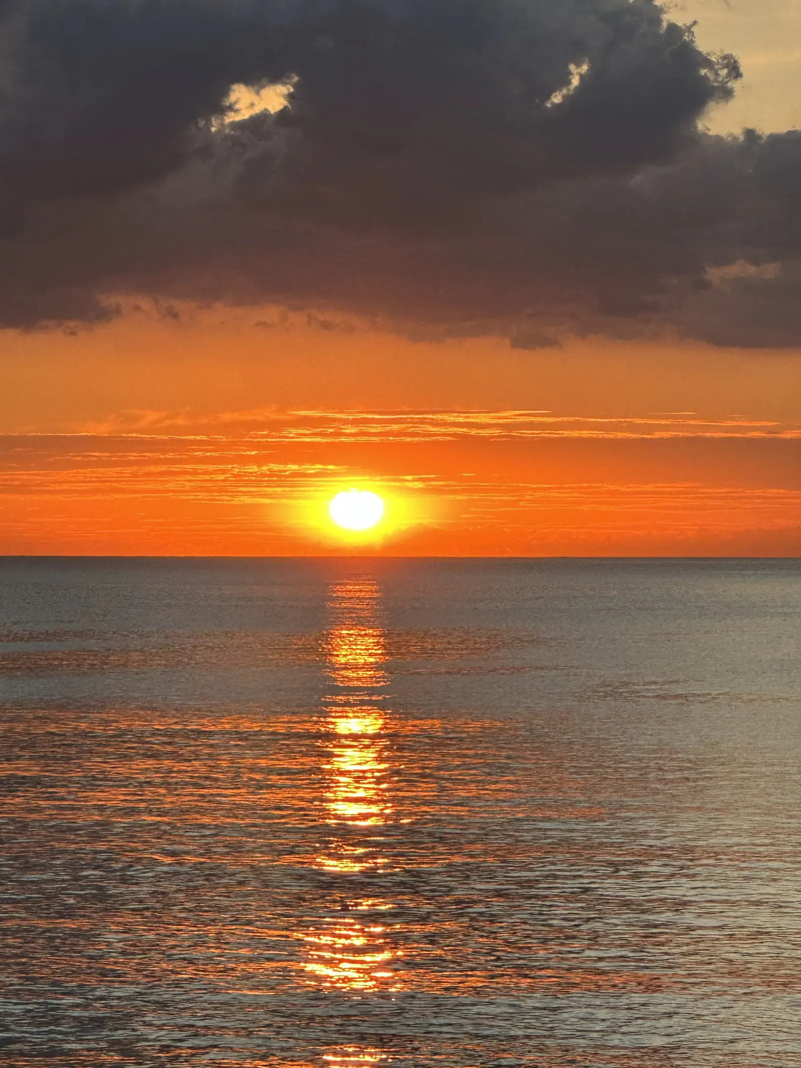 Sol entre faixas de nuvens, refletido no mar de Toque-Toque Grande