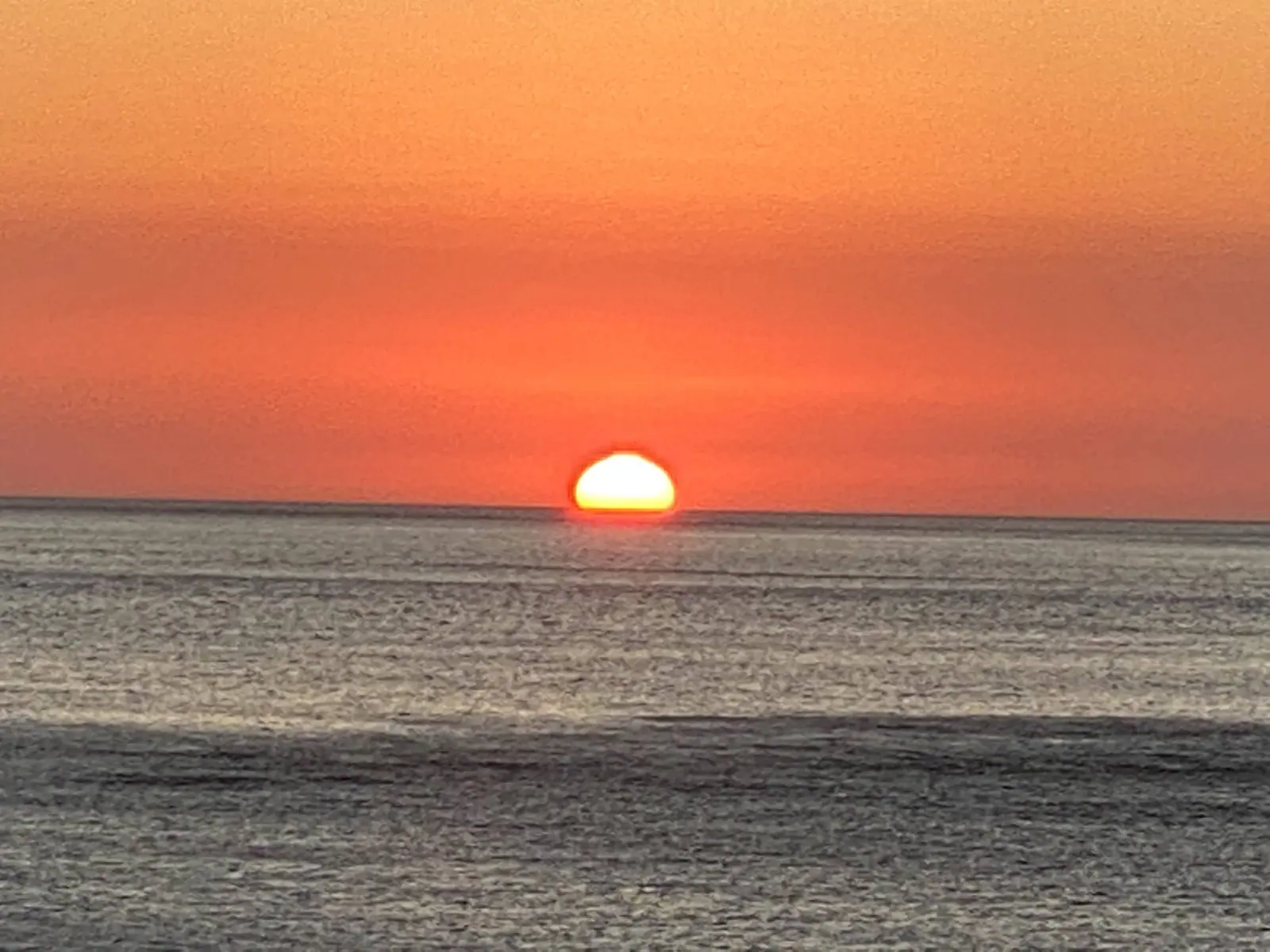 Sol tocando o mar de Toque-Toque Grande num céu laranja