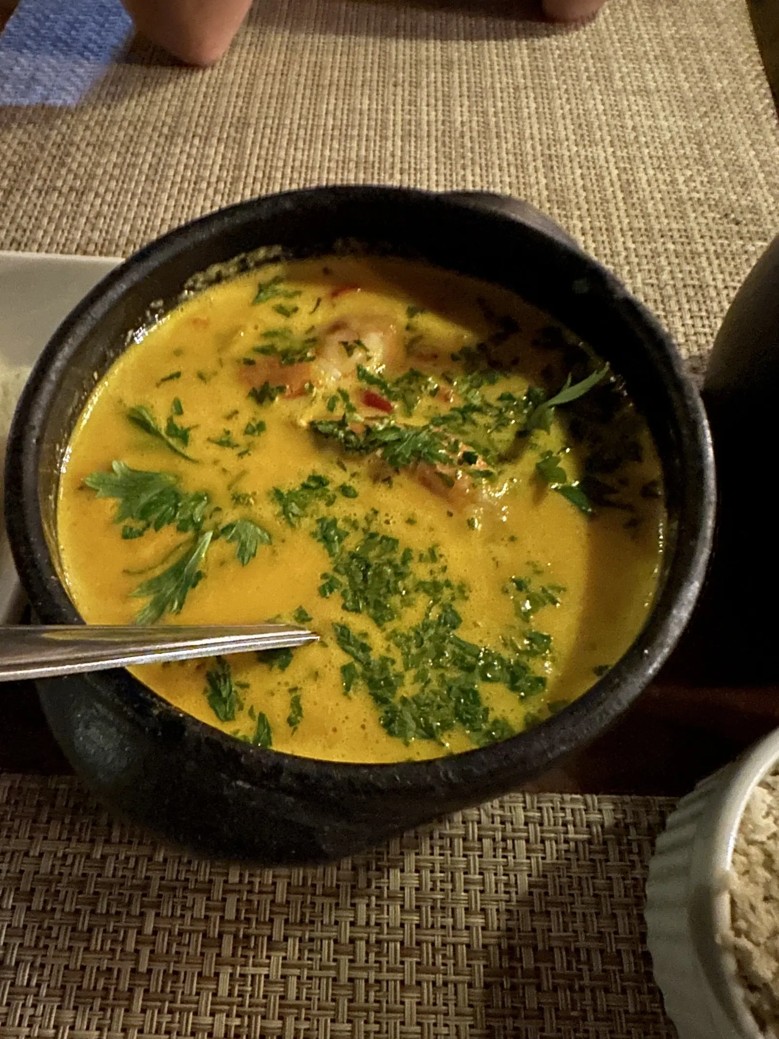 Prato caiçara com caldo amarelo e coentro servido na panela de barro em Toque-Toque Pequeno