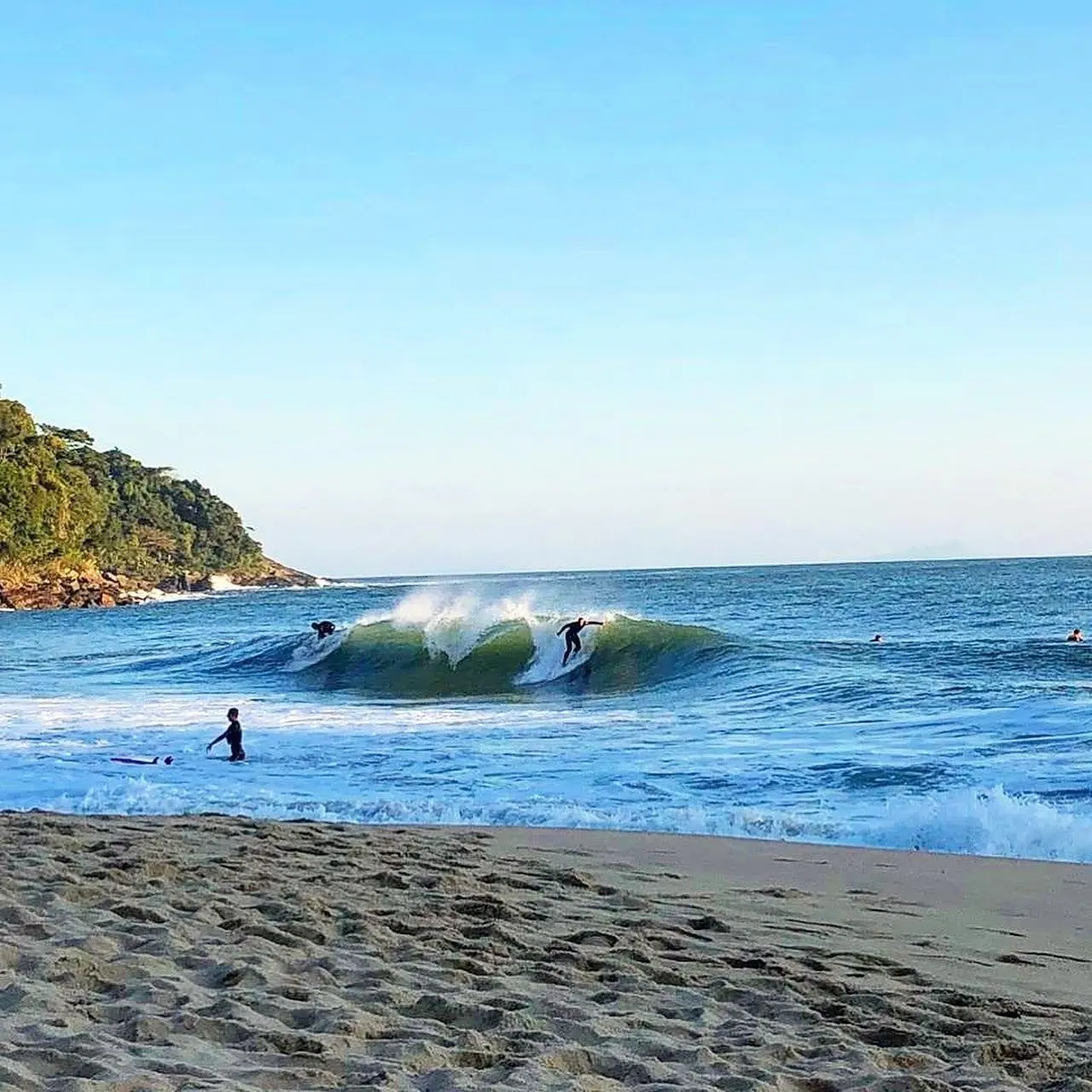 Tubo em Paúba visto da areia, com o costão de mata ao fundo