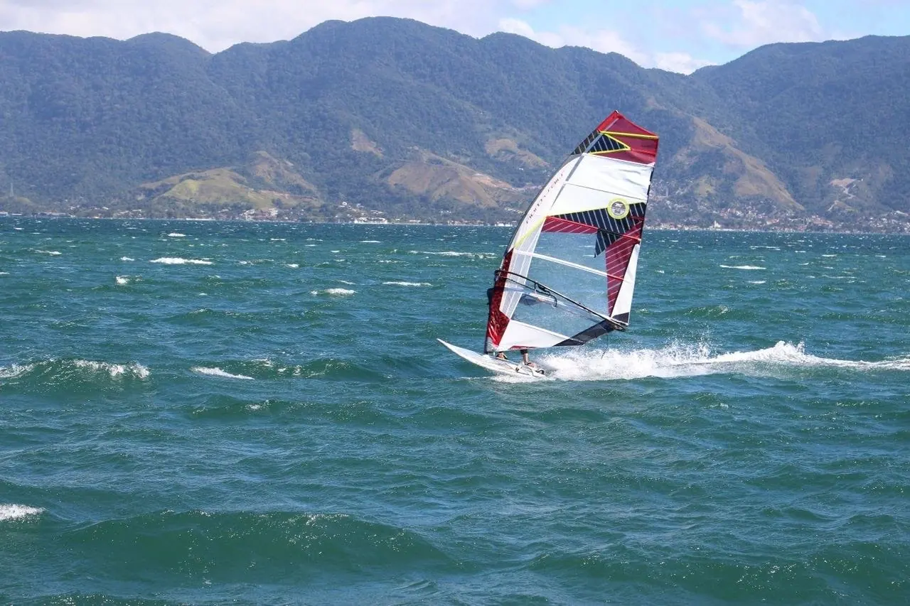 Windsurfista planando no canal de Ilhabela, com a serra ao fundo