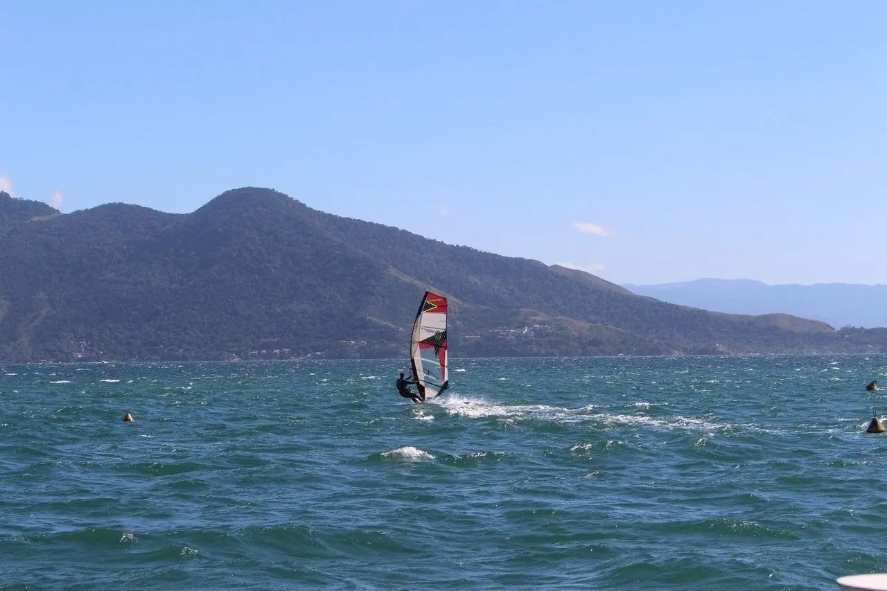 Windsurfista no canal entre Ilhabela e São Sebastião, com montanhas ao fundo